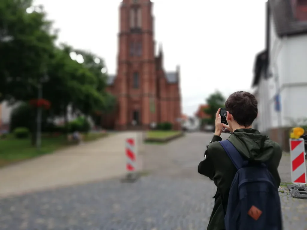 Jugendlicher fotografiert eine Kirche in der Altstadt.